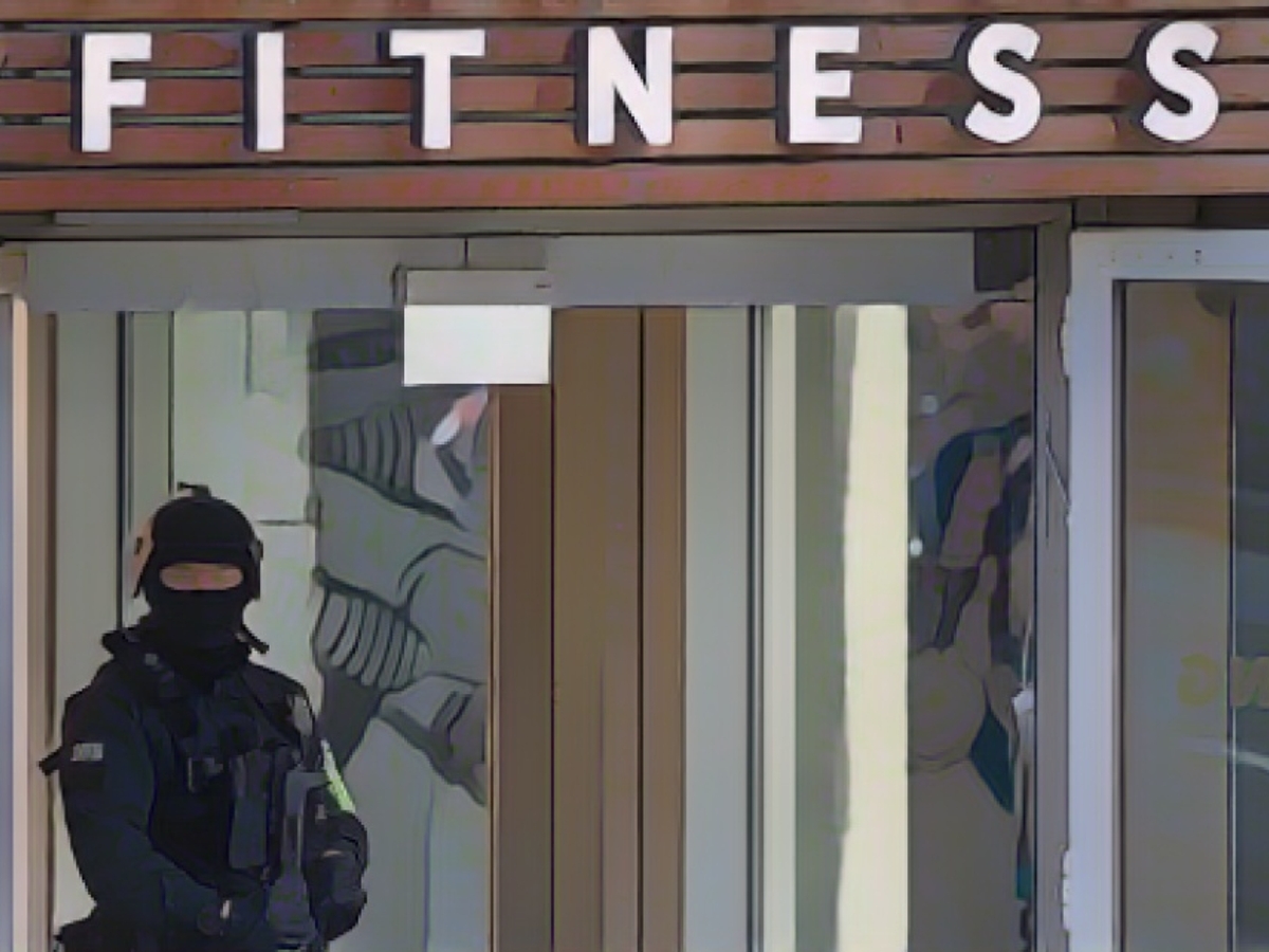 Ein schwer bewaffneter Polizist sichert das Duisburger Fitnessstudio nach dem Messerangriff