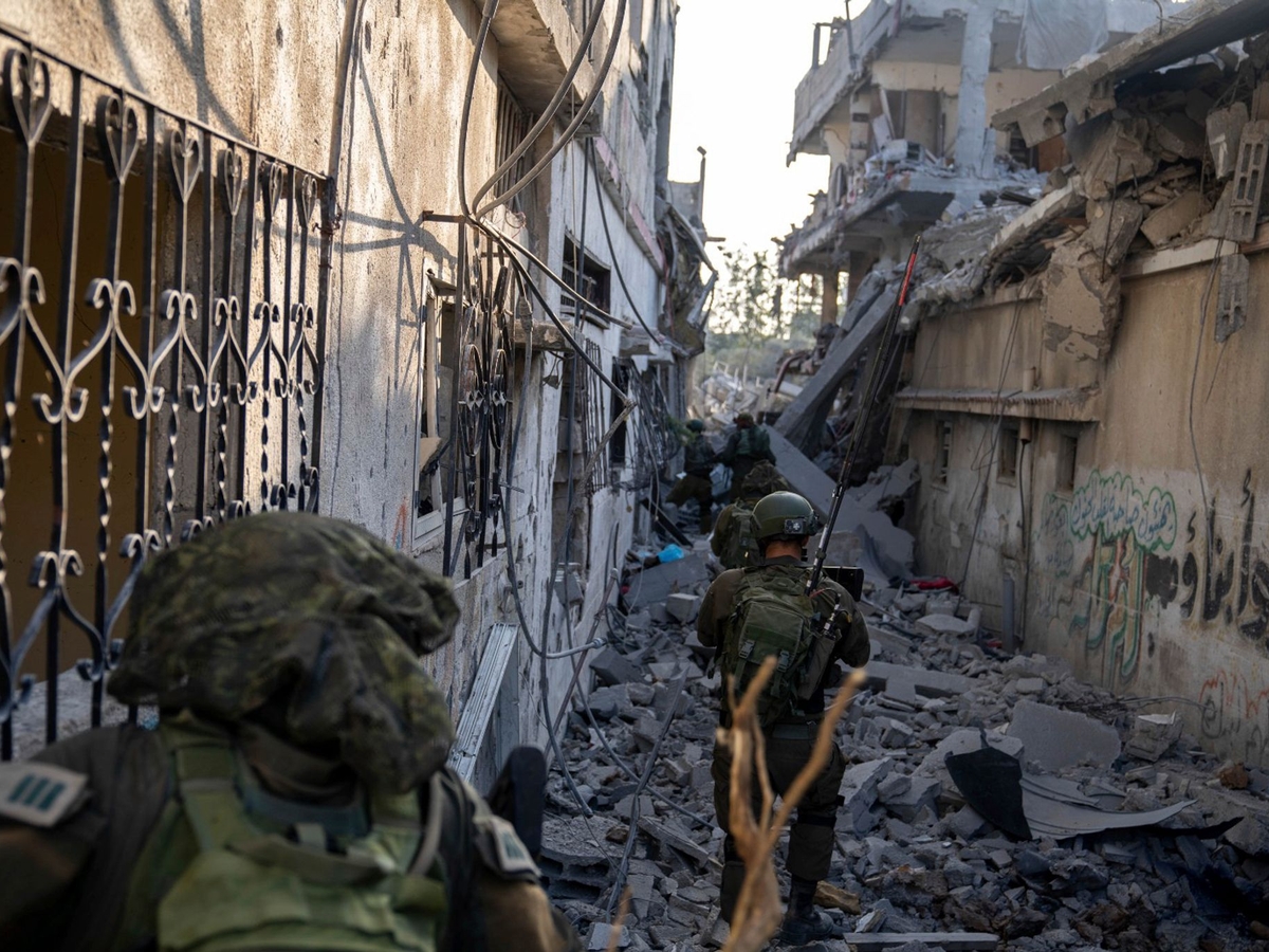 Израильские солдаты проходят между разрушенными домами: Израильские военные заявляют, что окружили город Газа.