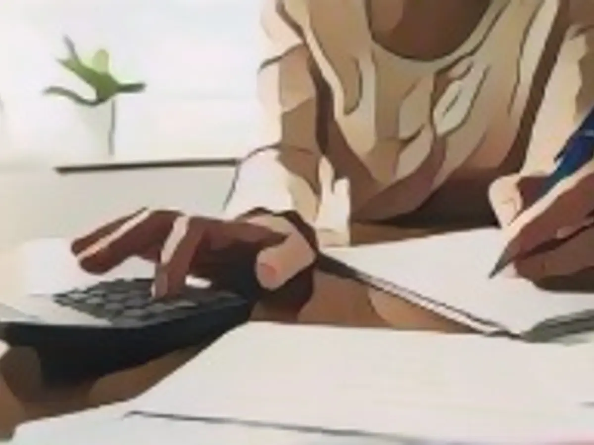 Primer plano de una mujer irreconocible utilizando una calculadora mientras revisa las facturas y las finanzas domésticas.
