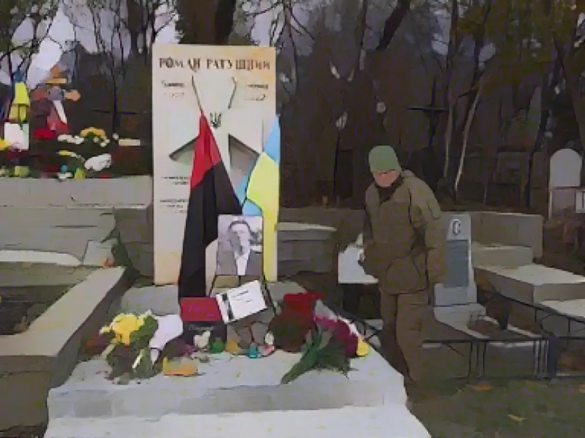 Taras Ratushnyy, Kasım 2023'te Ukrayna'nın Kiev kentindeki bir mezarlıkta oğlu Roman'ın mezarını ziyaret ediyor.