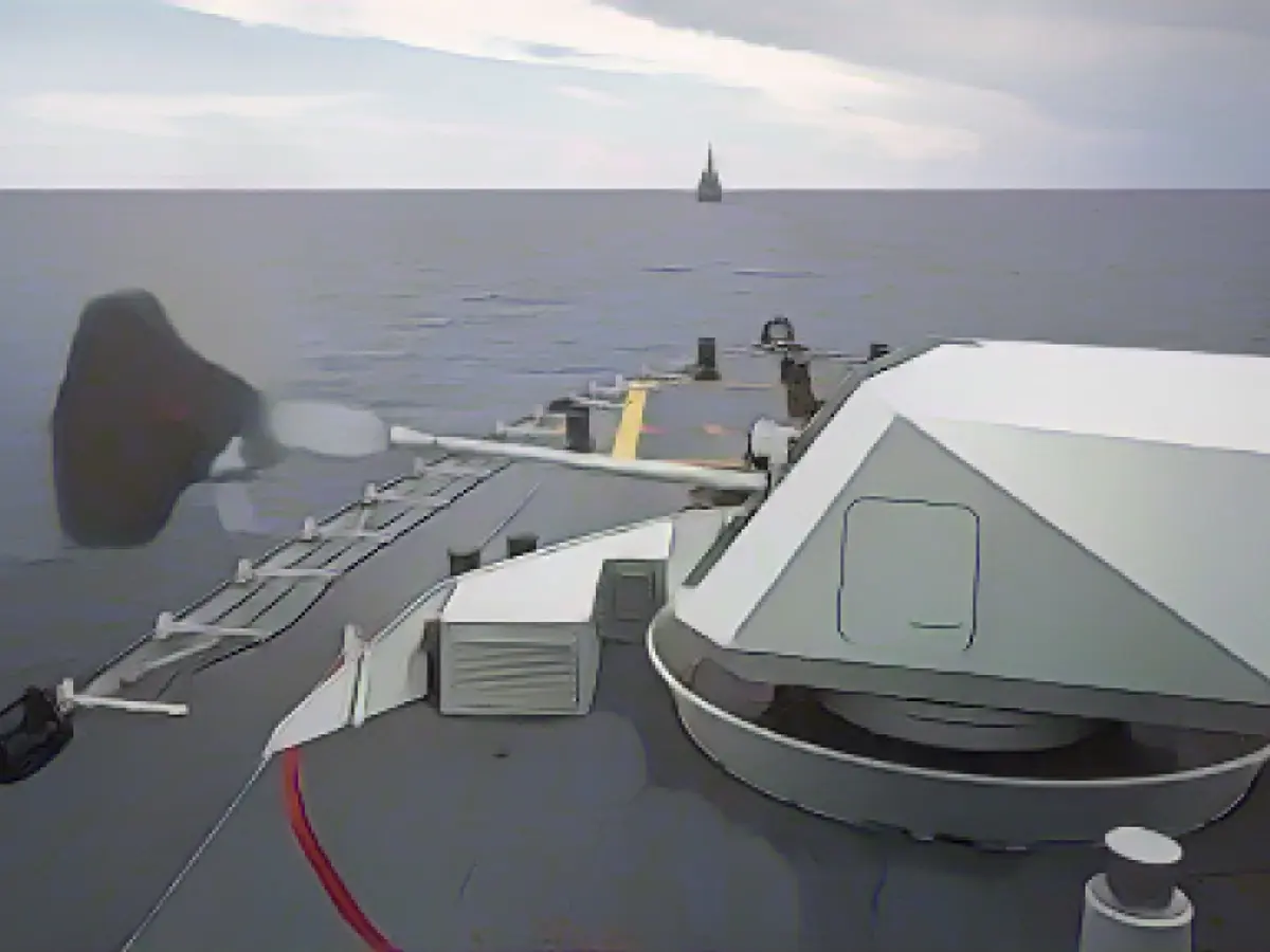 Корабль HMCS Ottawa стреляет из главного орудия в сторону дистанционной учебной мишени Hammerhead, в то время как корабли USS Rafael Peralta и HMAS Brisbane идут в строю во время учений по стрельбе с поверхности во время совместного развертывания в Южно-Китайском море 26 октября 2023 года.