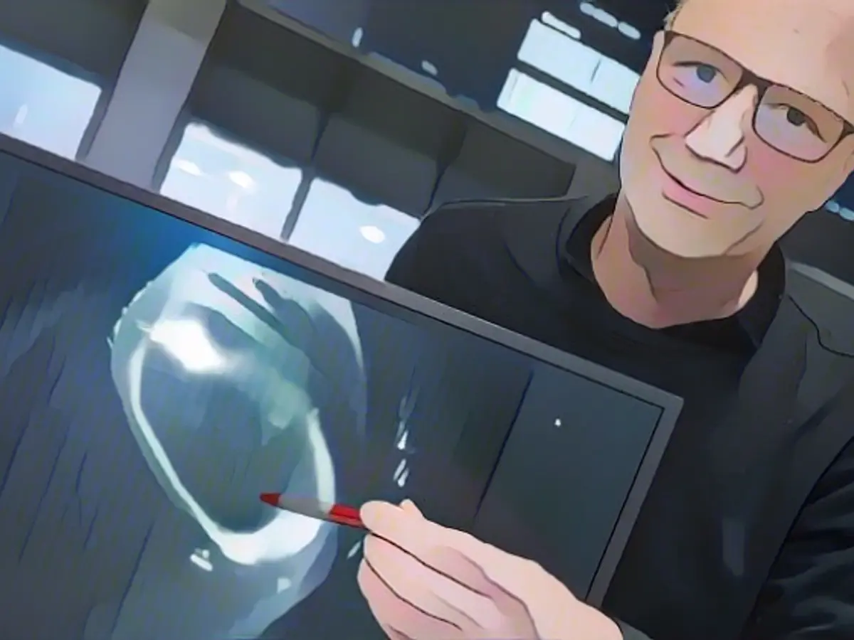 Thomas Klinger, Direktor des Max-Planck-Instituts für Plasmaphysik, hält einen Monitor in der Hand, auf dem ein Bild von Wasserstoffplasma zu sehen ist.