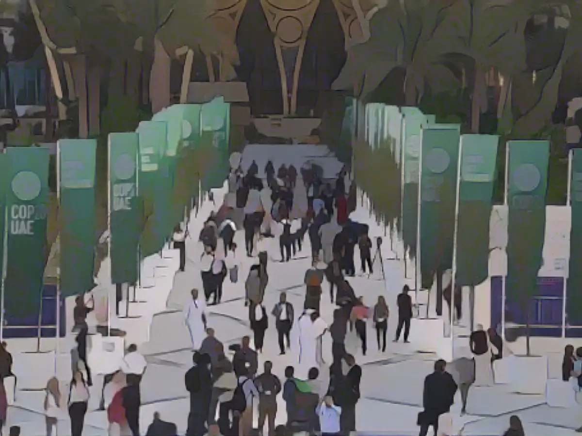 Oameni se plimbă în cadrul Summitului COP28 al ONU privind clima, luni, 4 decembrie 2023, în Dubai, Emiratele Arabe Unite.