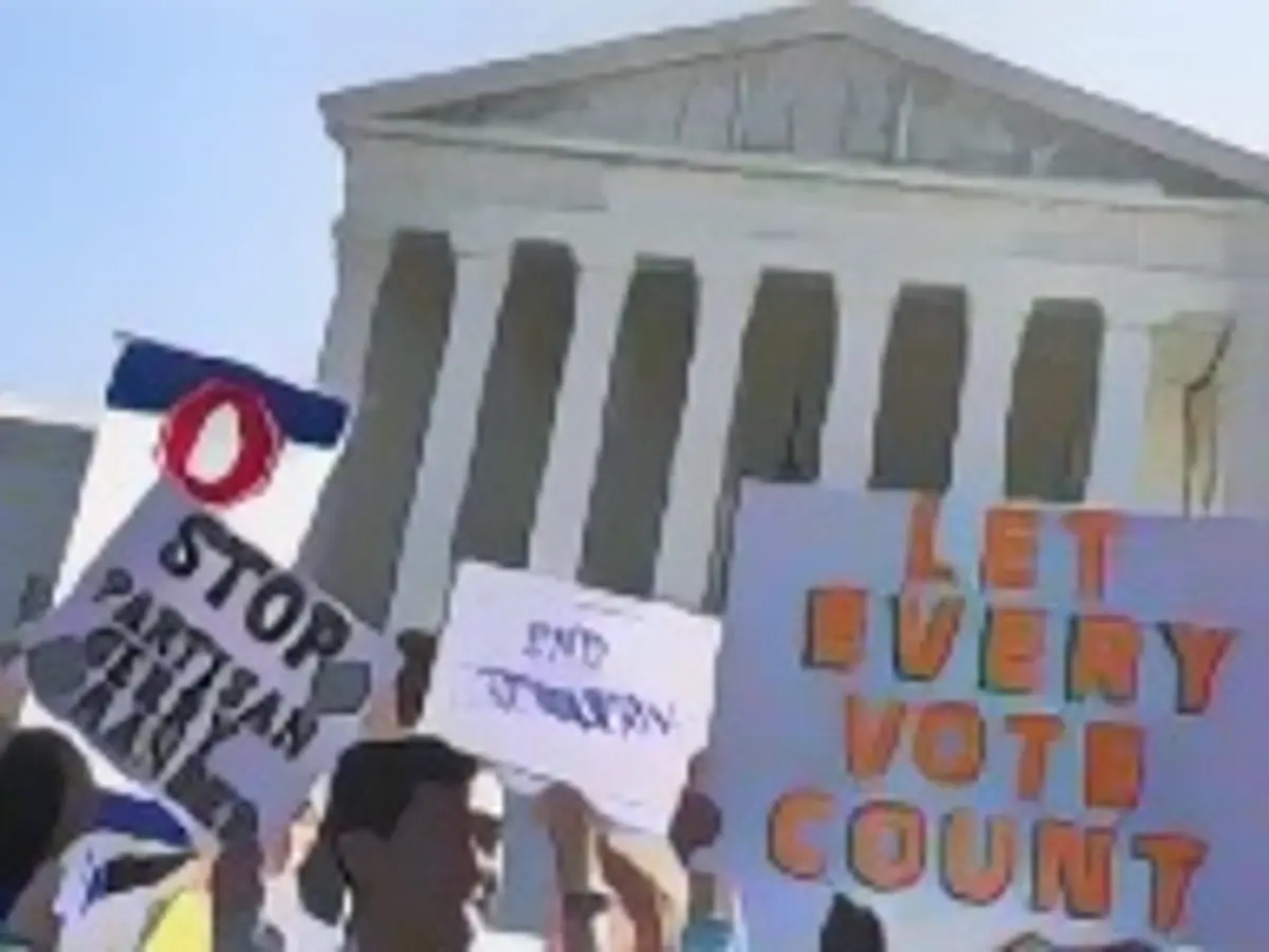 Während einer Kundgebung vor dem Obersten Gerichtshof der USA am 3. Oktober 2017 in Washington, D.C. halten Menschen Schilder hoch, die ein „Ende der Partisanenpolitik“ fordern.