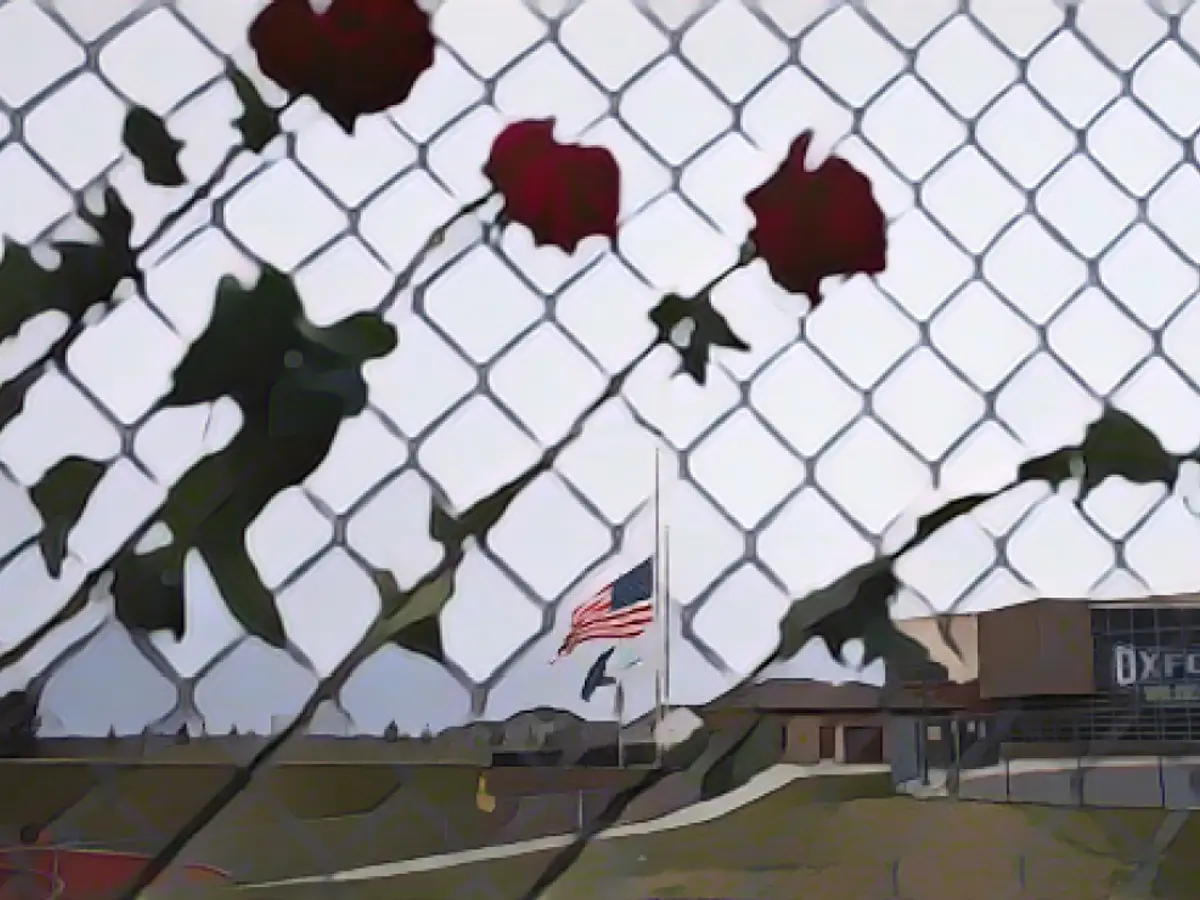 Розы свисают с забора в память о жертвах стрельбы в средней школе Оксфорда 7 декабря 2021 года в Оксфорде, штат Мичиган.