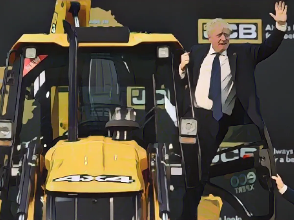 Der britische Premierminister Boris Johnson winkt während seines Besuchs in Indien im April von einem Bagger in einer JCB-Fabrik in Gujarat aus.