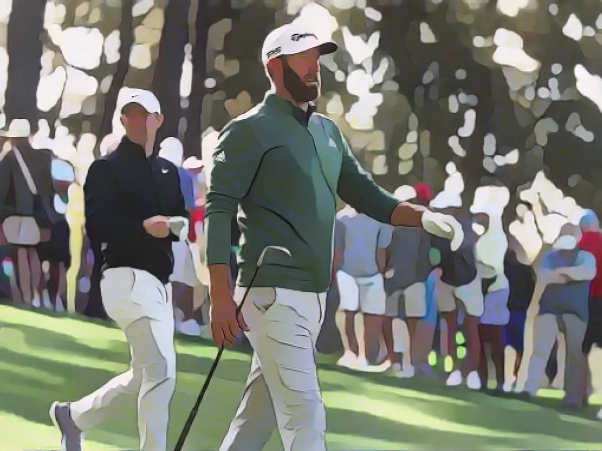 Titelverteidiger Dustin Johnson (rechts) und Rory McIlroy gehen nach dem Abschlag während einer Übungsrunde beim Masters das vierte Fairway entlang.