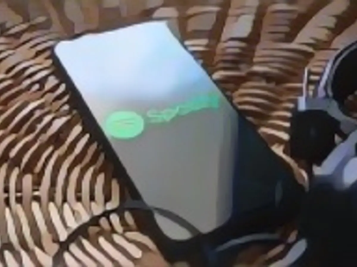 Headphones connected to a mobile phone with the Spotify logo on its screen in Athens, Greece on July 16, 2023