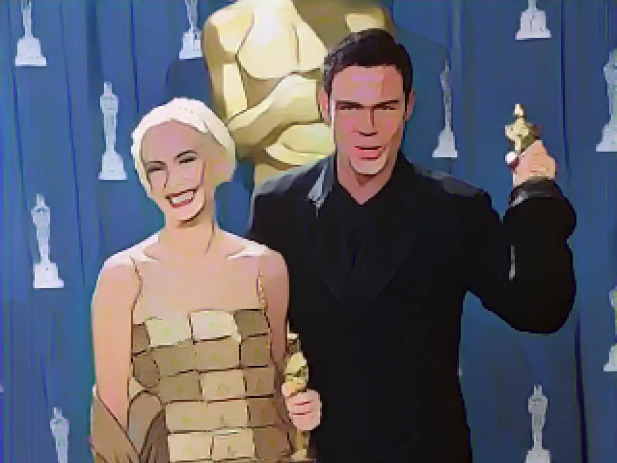 Australienii Lizzy Gardiner și Tim Chappel țin în mână premiile Oscar pe care le-au primit pentru cel mai bun design de costume pentru munca lor în filmul 
