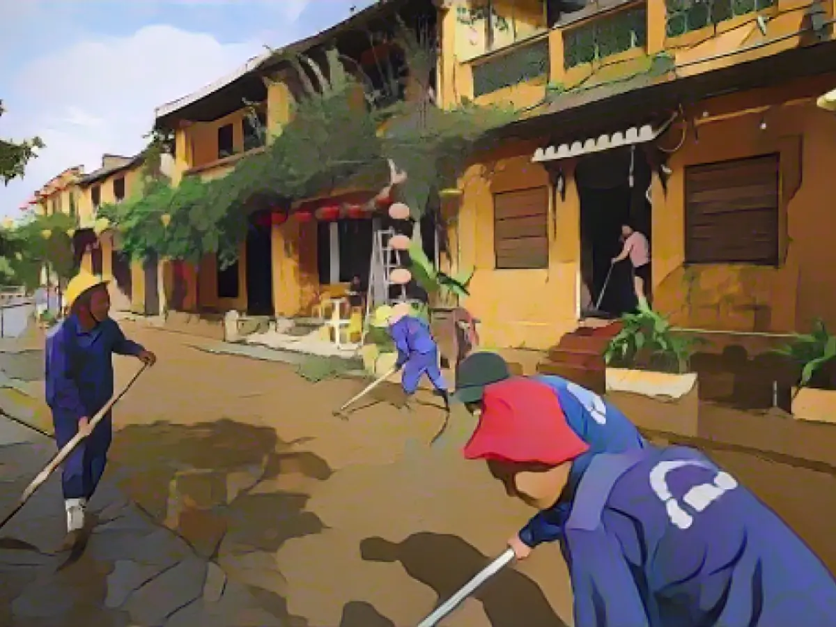 Муниципальные служащие и жители убирают улицы после отступления воды в старом городе Хойан, внесенном в список всемирного наследия ЮНЕСКО, 30 октября 2020 года, после тайфуна 