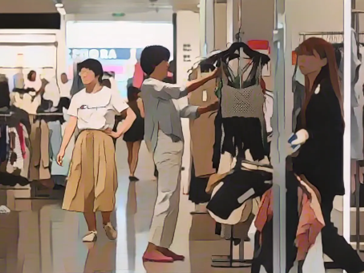 Uma mulher escolhe roupa num centro comercial em Pequim, a 15 de junho de 2023.