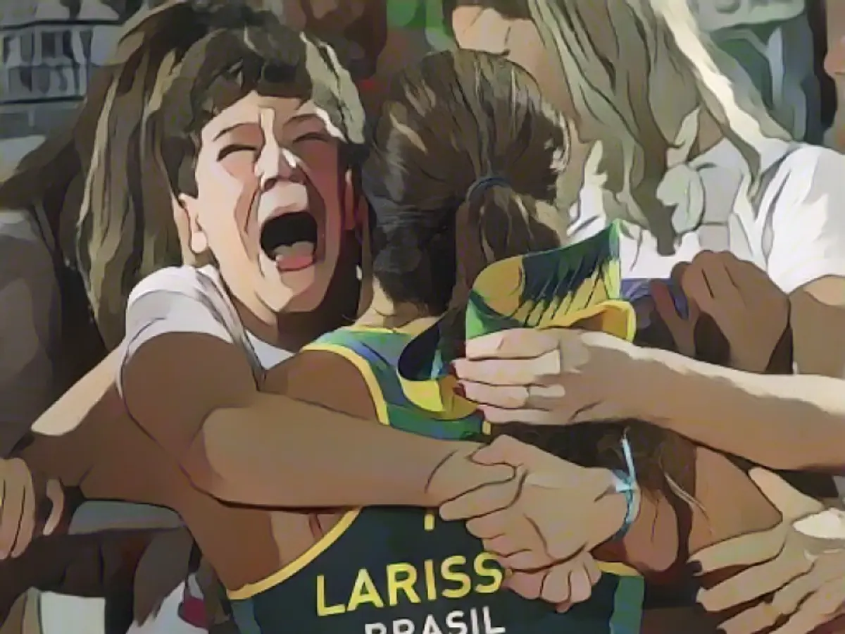 Бразильская спортсменка Лариса Франка (в центре) обнимается с болельщиками после выхода в полуфинал женского турнира по пляжному волейболу вместе с партнершей Талитой Антунес.