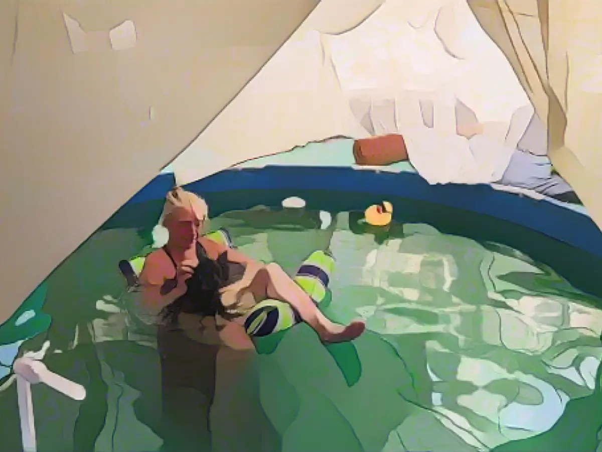 Дот из художественной галереи House of Dots расслабляется в бассейне со своей собакой, когда они охлаждаются в условиях сильной жары в среду в Слэб-Сити недалеко от Ниланда, штат Калифорния.