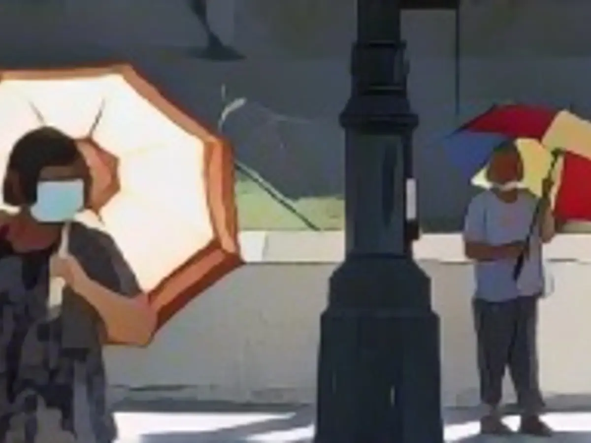 Люди идут с зонтиками в тени в Лос-Анджелесе, Калифорния, в четверг.
