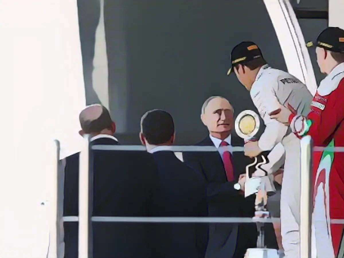 Росбергу вручает трофей победителя президент России Владимир Путин