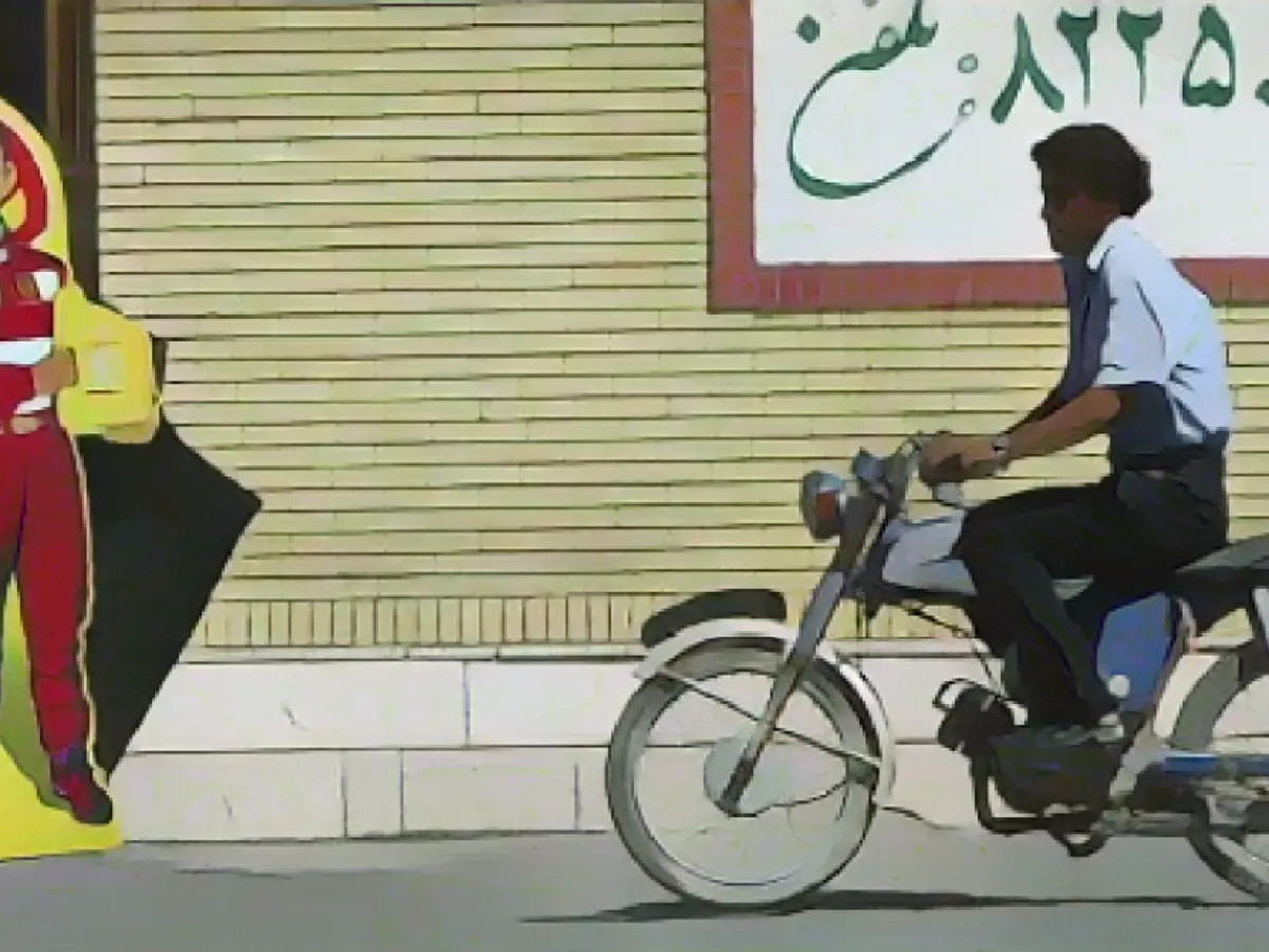 Мужчина проезжает мимо плаката с изображением Шумахера в Бахремане, Иран, 2005 год.