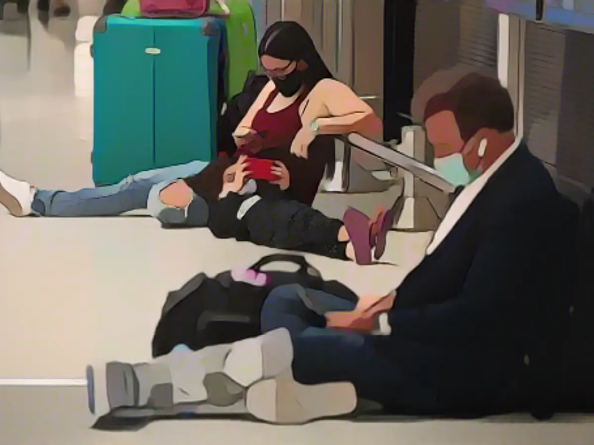 Женщина и ребенок ждут своего рейса вместе с другими пассажирами в международном аэропорту Майами 27 декабря 2021 года.