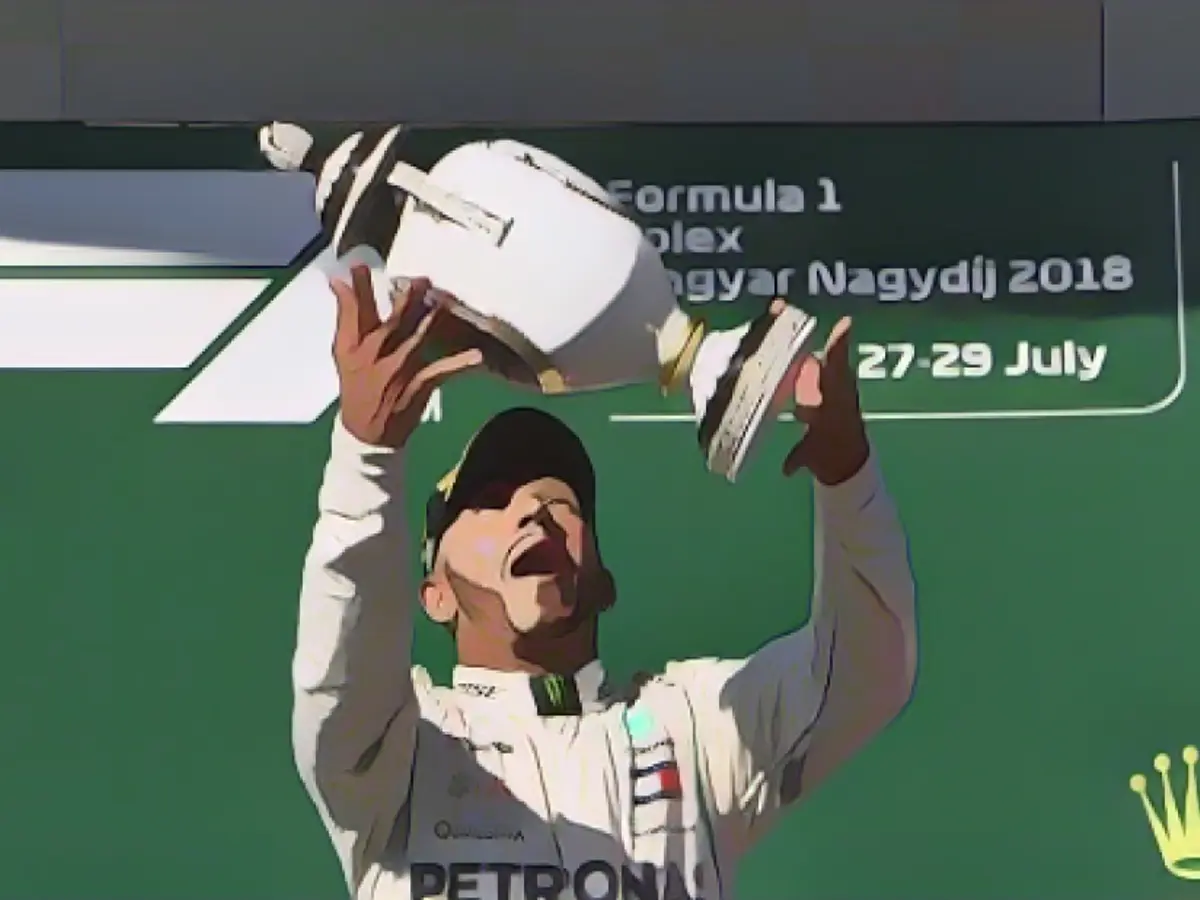 Lewis Hamilton celebra con el trofeo en el podio tras ganar el Gran Premio de Hungría en Hungaroring, cerca de Budapest, y ampliar su ventaja en el título sobre Sebastian Vettel a 24 puntos.