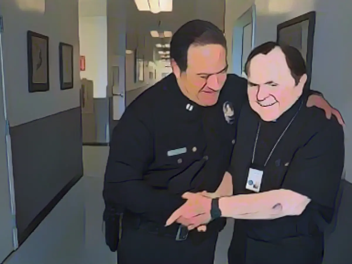 Капитан полиции Лос-Анджелеса Аарон Понс (слева) пожимает руку монсеньору Фрэнку Хиксу из капелланского корпуса полиции Лос-Анджелеса.