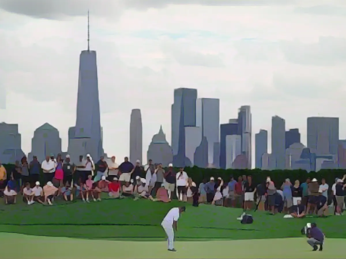 Lo spagnolo Jon Rahm esegue un putt sul 18° green mentre in lontananza si staglia lo skyline di Manhattan.