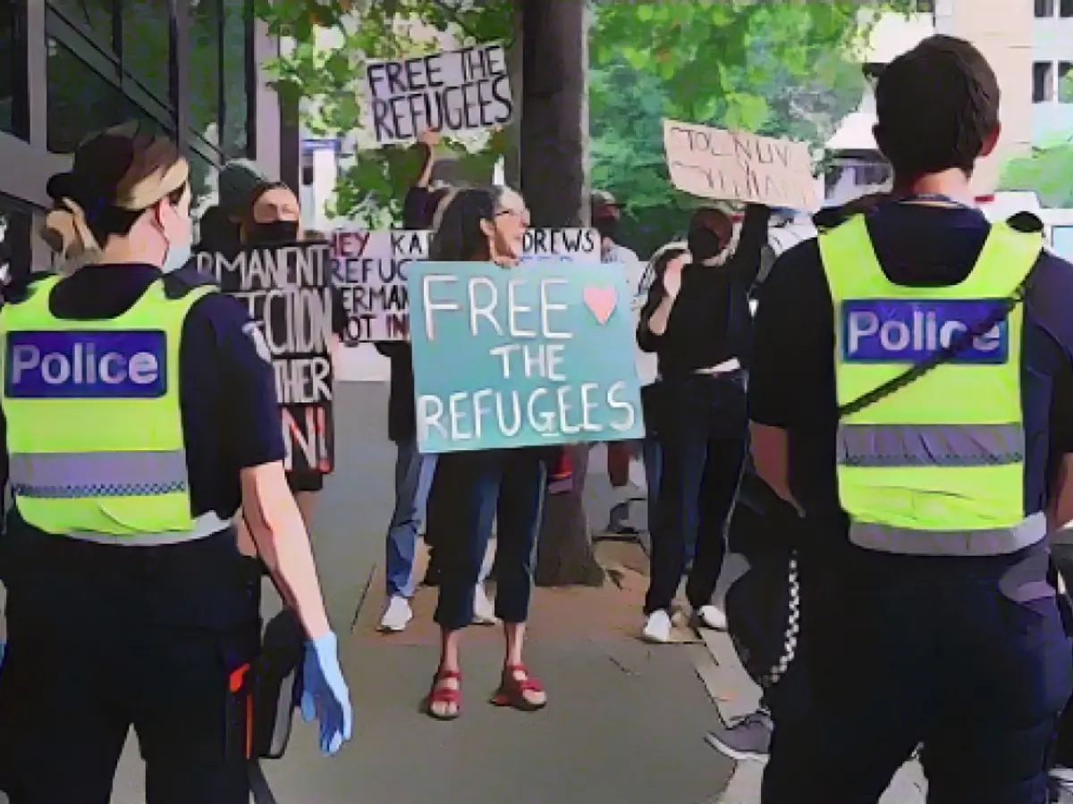 Polis personeli, 10 Ocak'ta Avustralya'nın Melbourne kentinde Sırp tenisçi Novak Djokovic'in tutulduğuna inanılan Park Otel'in önünde toplanan mülteci yanlısı protestocuları izliyor.