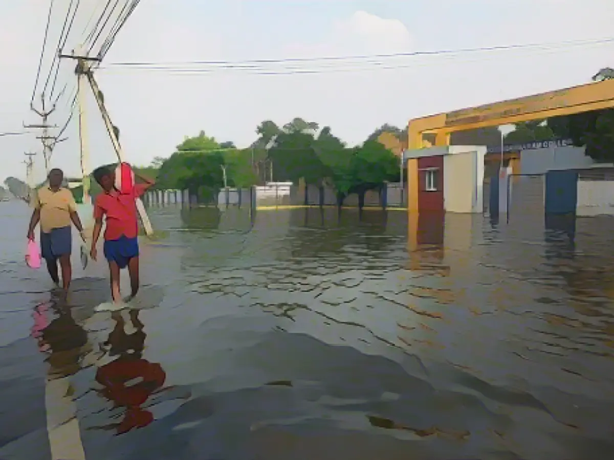 Menschen gehen am 20. Dezember 2023 durch eine überflutete Straße in Thoothukudi.