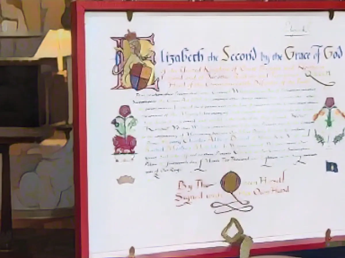 Regina Elisabeta a II-a a semnat Instrumentul de consimțământ, în fotografie, notificarea oficială de aprobare a nunții în scris caligrafic elaborat, emis sub Marele Sigiliu al Regatului.