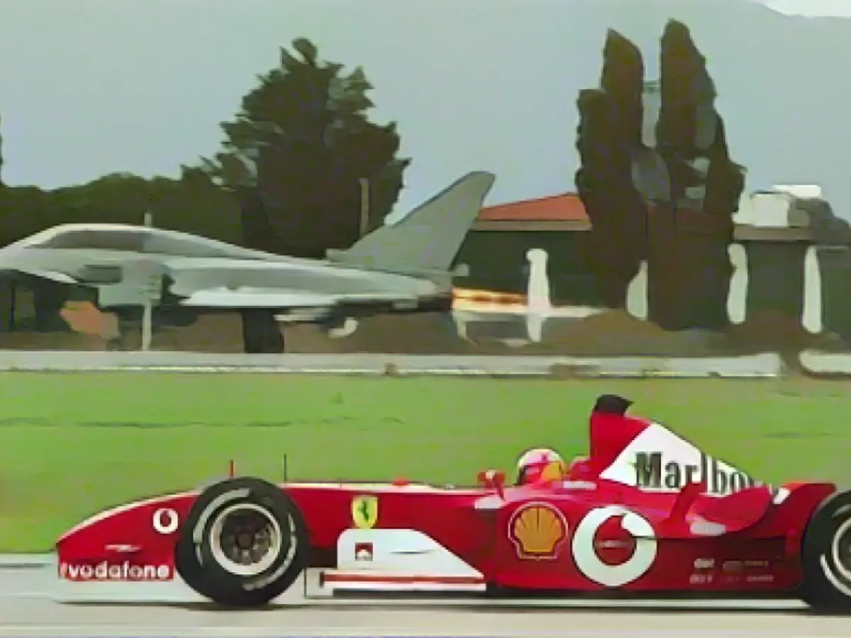 Schumacher dirige o seu Ferrari à frente de um Eurofighter na pista de um aeroporto militar em Grosseto, Itália, em 2003.