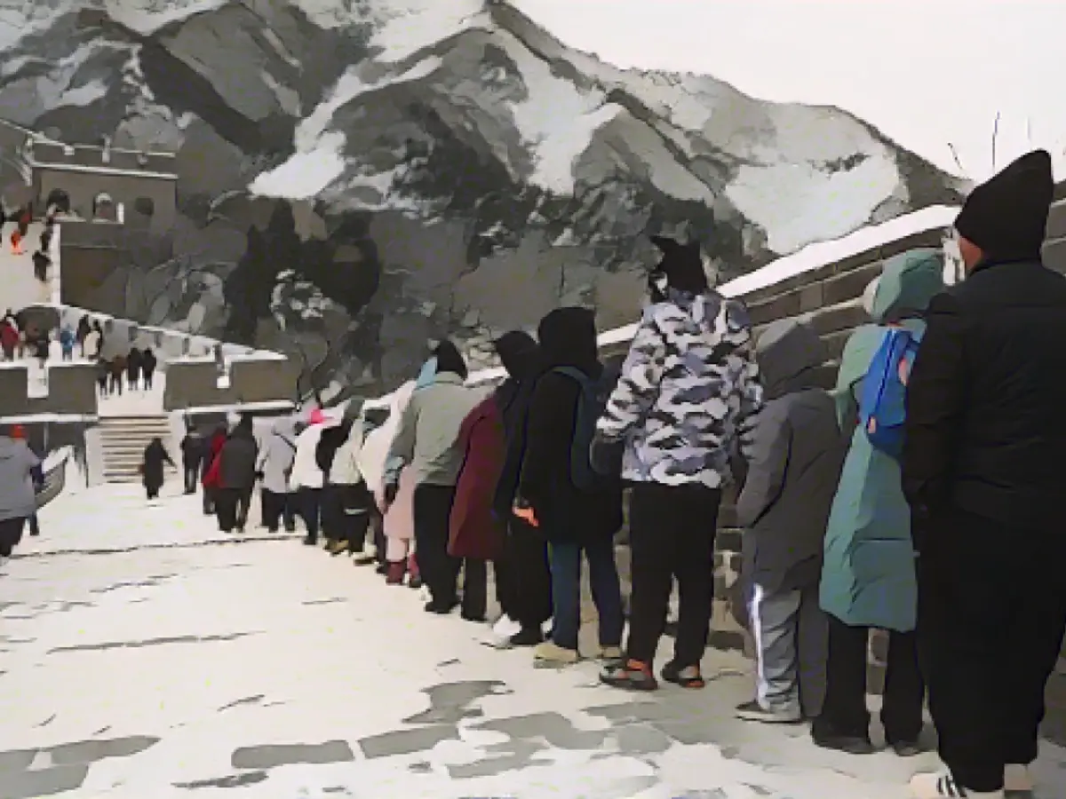 Un grupo de personas sujeta una cuerda mientras desciende por un tramo helado de la Gran Muralla China.