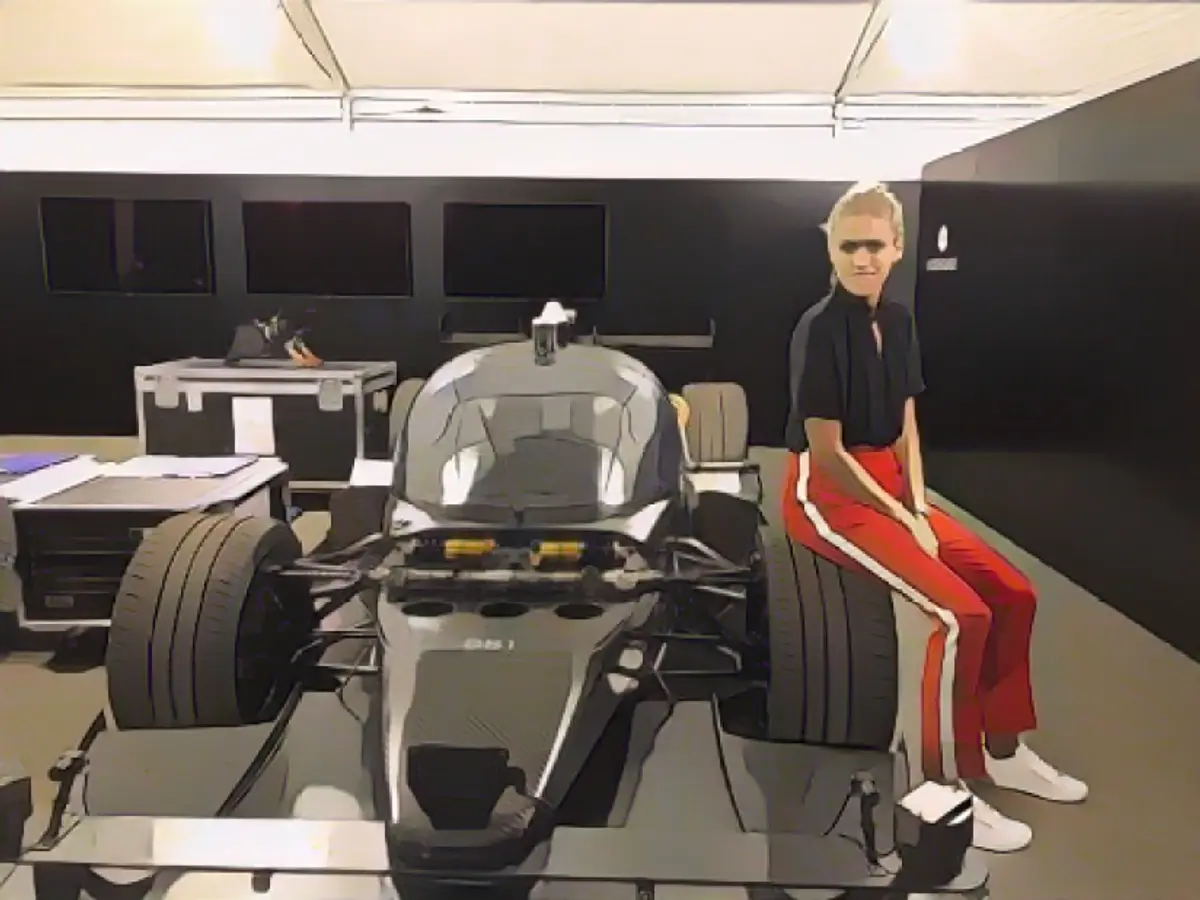 Ники Шилдс позирует со своим соперником, гоночным автомобилем DevBot с искусственным интеллектом, на гонках Hong Kong ePrix в декабре этого года.