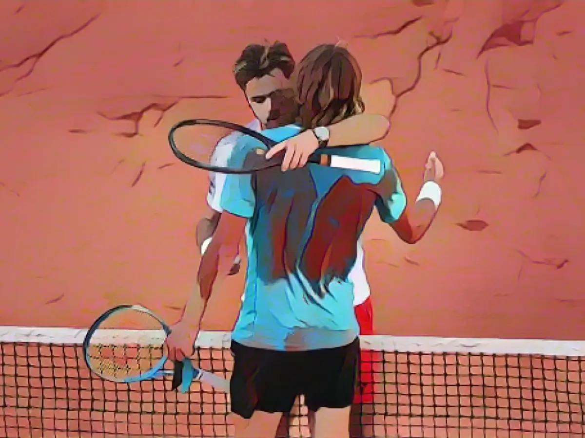 Stan Wawrinka ve Stefanos Tsitsipas (mavi tişörtlü) Fransa Açık maratonunun ardından kucaklaşıyor.