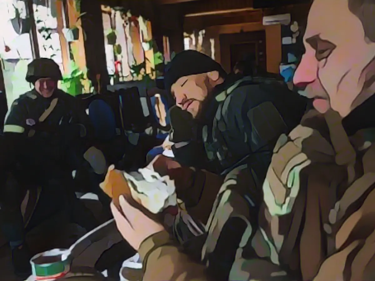 Ярослав Амосов, положив голову на руки, вместе с другими украинскими солдатами готовится к встрече с российскими войсками в Ирпене, Украина.