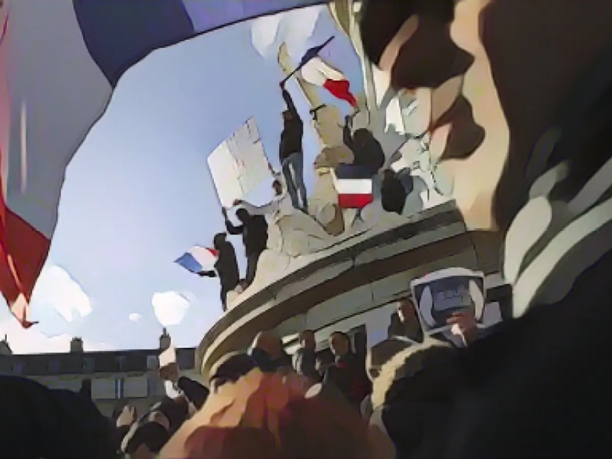 Demonstranții flutură steaguri pe monumentul din centrul Place de la Republique înainte de miting.
