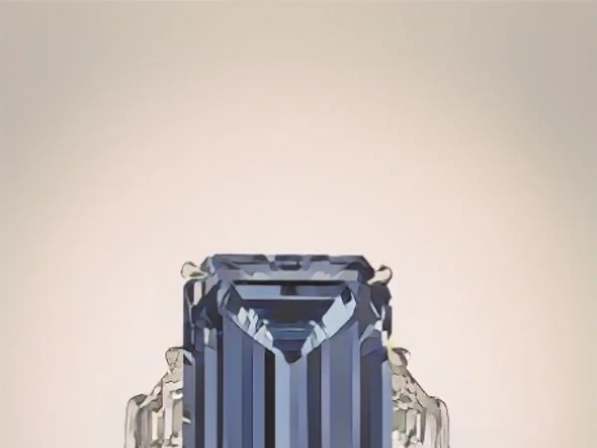 Piatra Fancy Vivid de 14,62 carate este montată pe un inel de platină și este flancată de o parte și de alta de un diamant în formă de trapez.