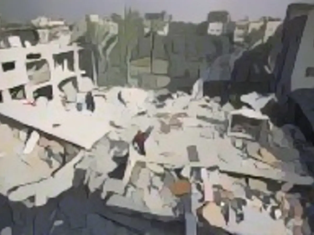 Filistinliler 12 Aralık'ta Gazze'nin Deyr el-Belah kentinde İsrail saldırılarının ardından yıkılan bir binanın enkazı altında kullanılabilir eşyalarını toplamaya çalışırken yıkılmış bir yerleşim alanının havadan görünümü.