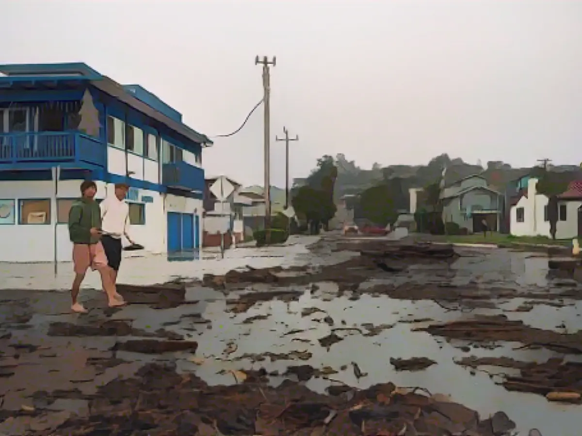 Doi bărbați se plimbă printre resturile oceanului în cartierul Rio Del Mar din Aptos, în comitatul Santa Cruz.