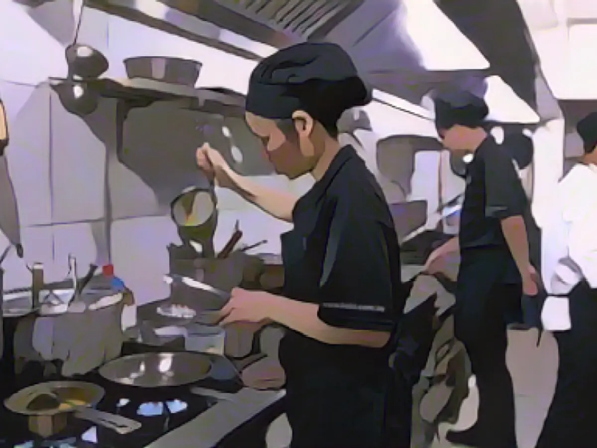 Des employés travaillent à la chaîne dans la cuisine du KOTO de Hanoï.