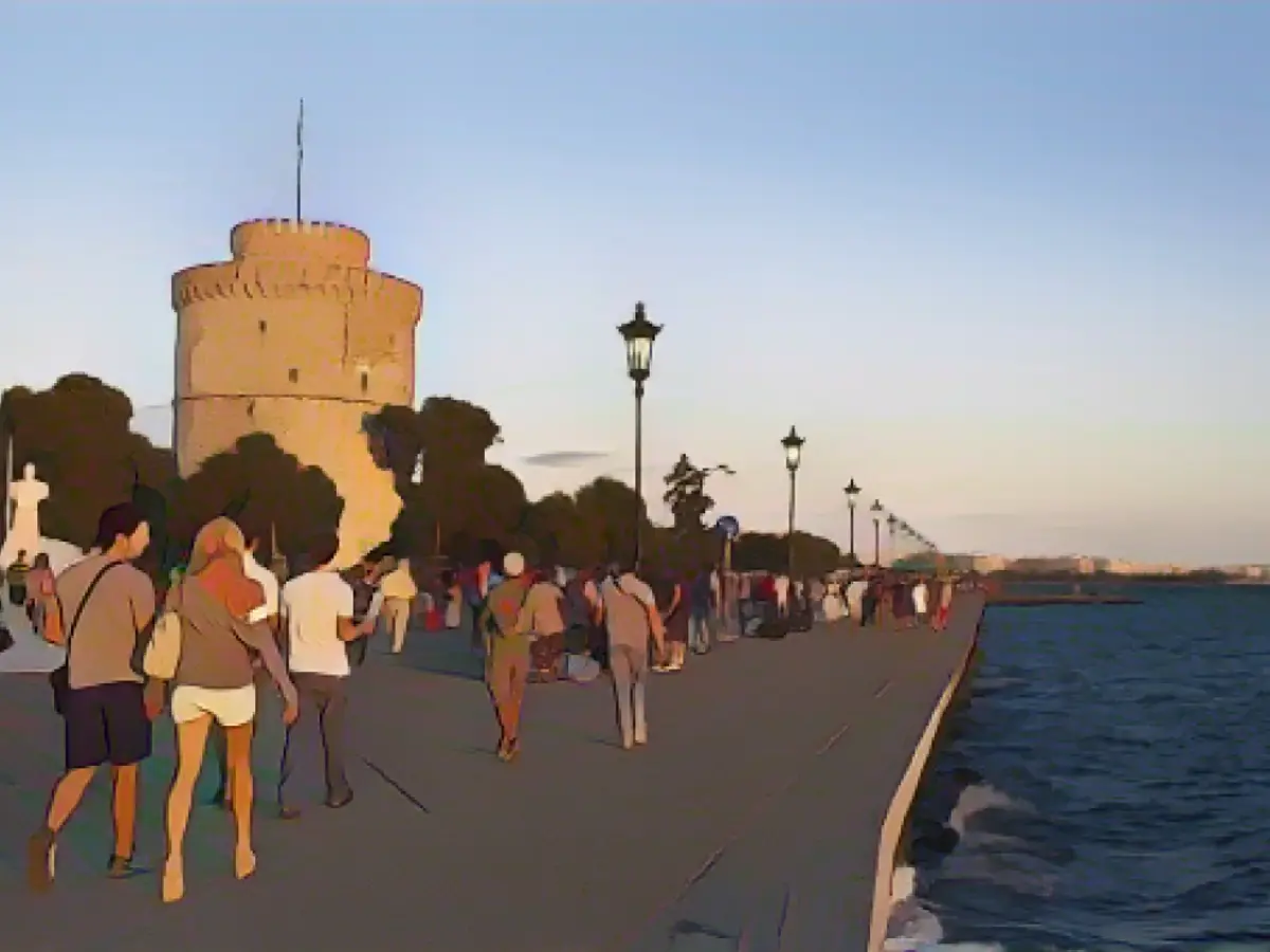 Люди прогуливаются у моря в Салониках, втором городе Греции.