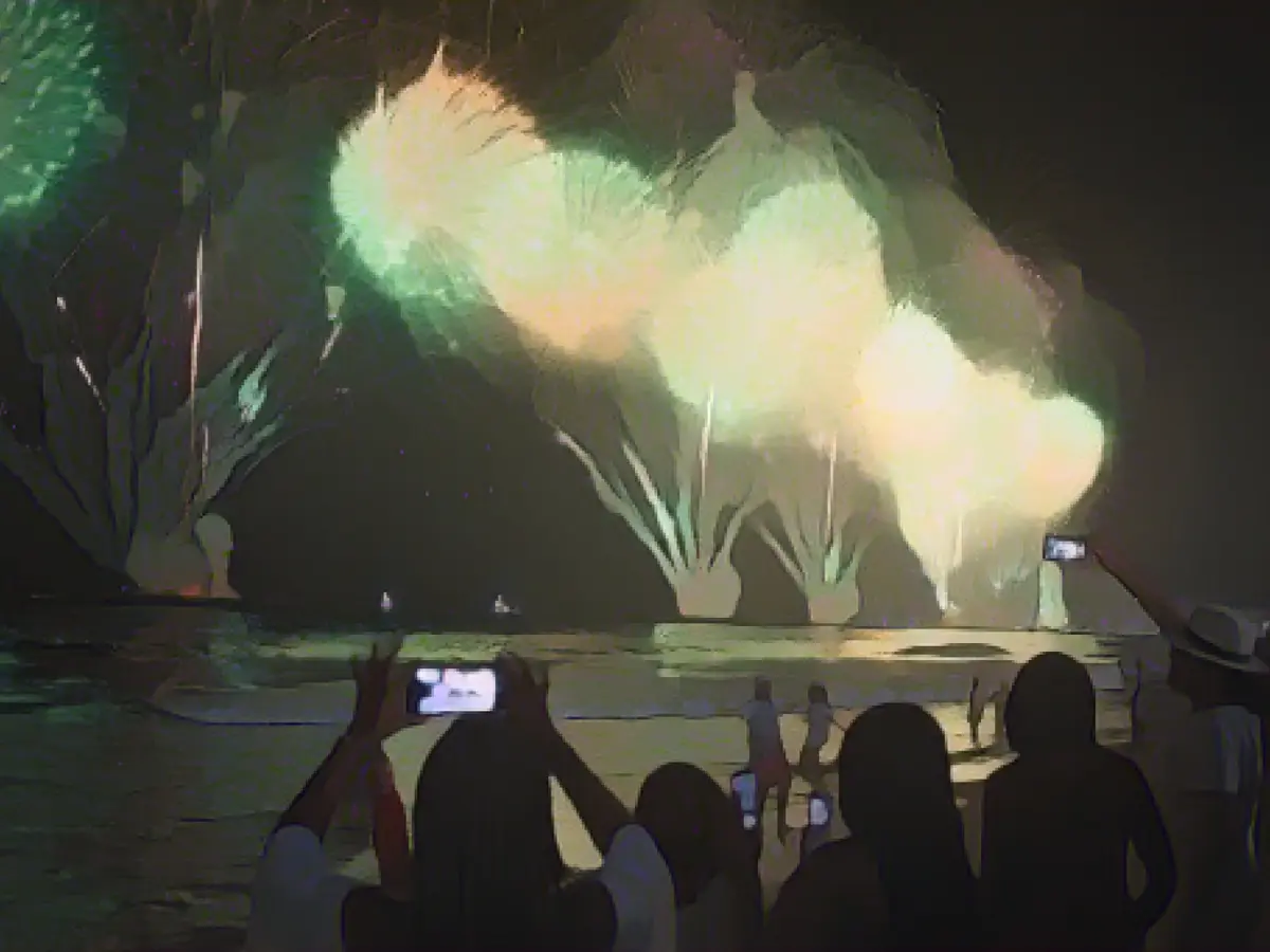 Люди празднуют, когда традиционный новогодний фейерверк озаряет небо на пляже Копакабана в Рио-де-Жанейро 1 января 2023 года.