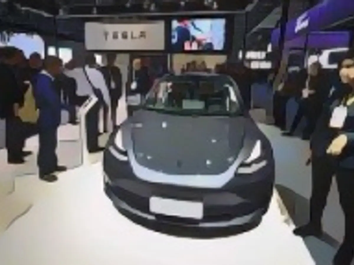 Люди смотрят на Tesla Model 3 на стенде Tesla в третий день 2-й Китайской международной импортной выставки (CIIE) в Национальном выставочном и конгресс-центре 7 ноября 2019 года в Шанхае, Китай.