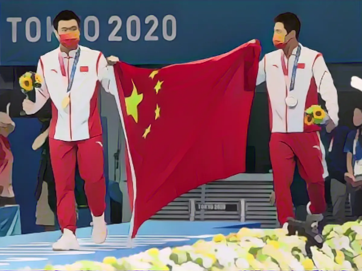 Chinezii Cao Yuan (stânga) și Yang Jian își sărbătoresc medaliile obținute în finala masculină de la platforma de 10 m la Jocurile Olimpice de la Tokyo.