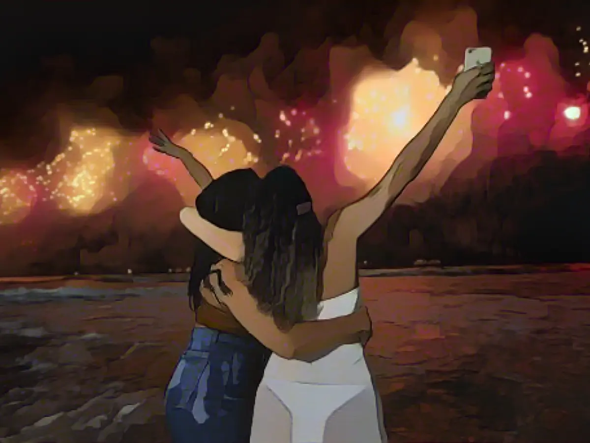 Люди встречают Новый год, наблюдая за взрывами фейерверков над пляжем Копакабана в Рио-де-Жанейро, Бразилия, рано утром в воскресенье, 1 января 2023 года.