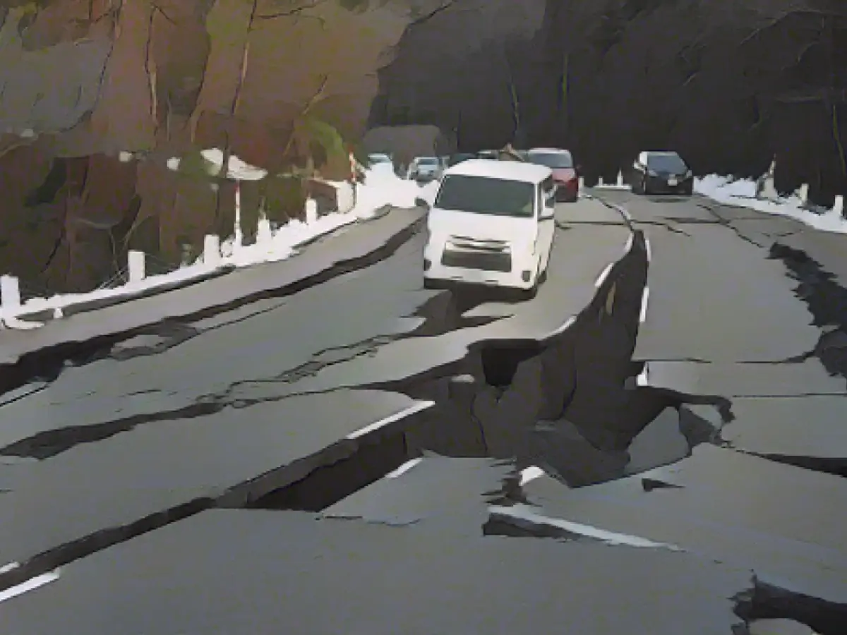 Mașini sunt blocate în crăpături, deoarece drumul a fost avariat de mai multe cutremure puternice, pe 2 ianuarie 2024, în Noto, Ishikawa, Japonia.