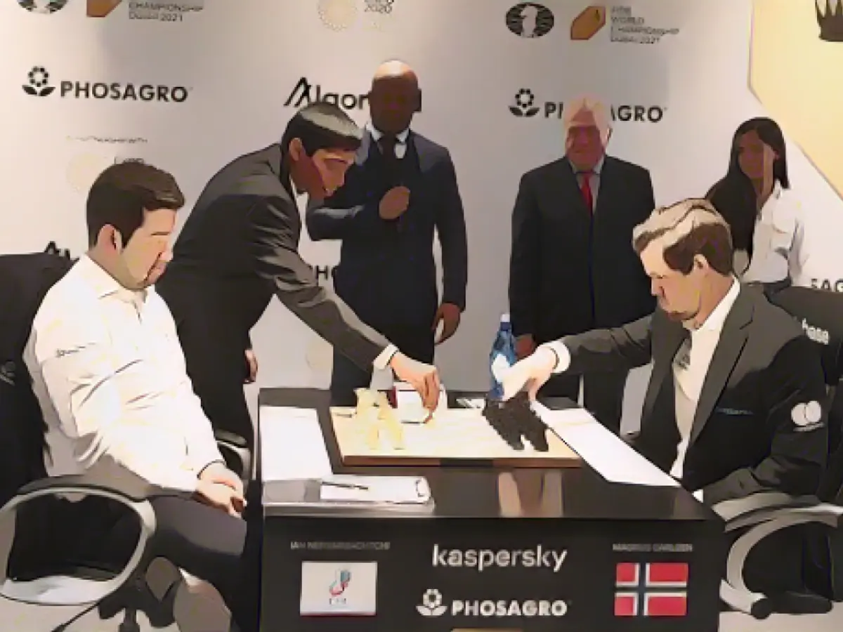 Прагг передвигает шахматную фигуру во время матча между Яном Непомнящим (слева) и Магнусом Карлсеном (справа) на чемпионате мира по шахматам ФИДЕ в рамках ЭКСПО-2020 в Дубае 7 декабря 2021 года.