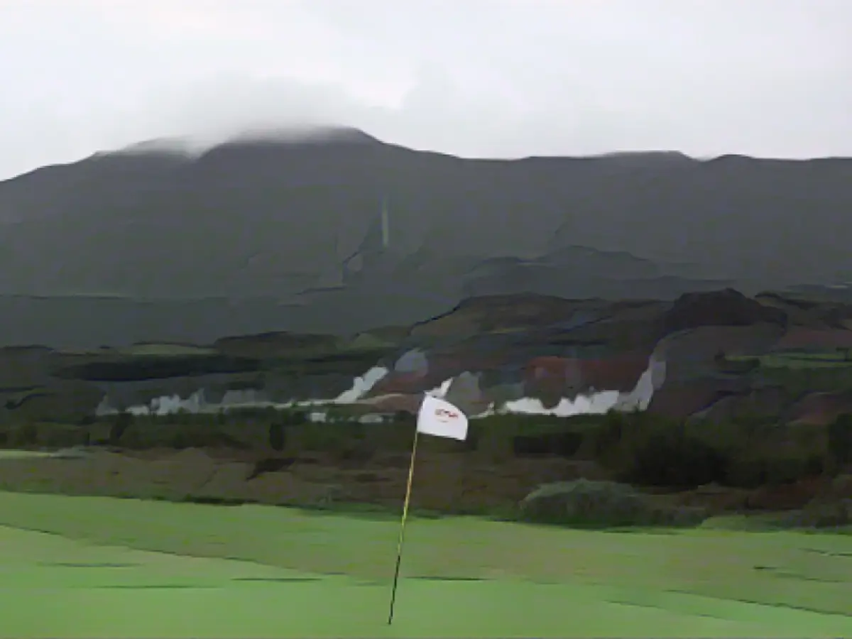 Geysir Golf Kulübü'nün sekizinci çukurundaki yeşil alan ve arkasındaki doğal Geysirlerden çıkan buhar.