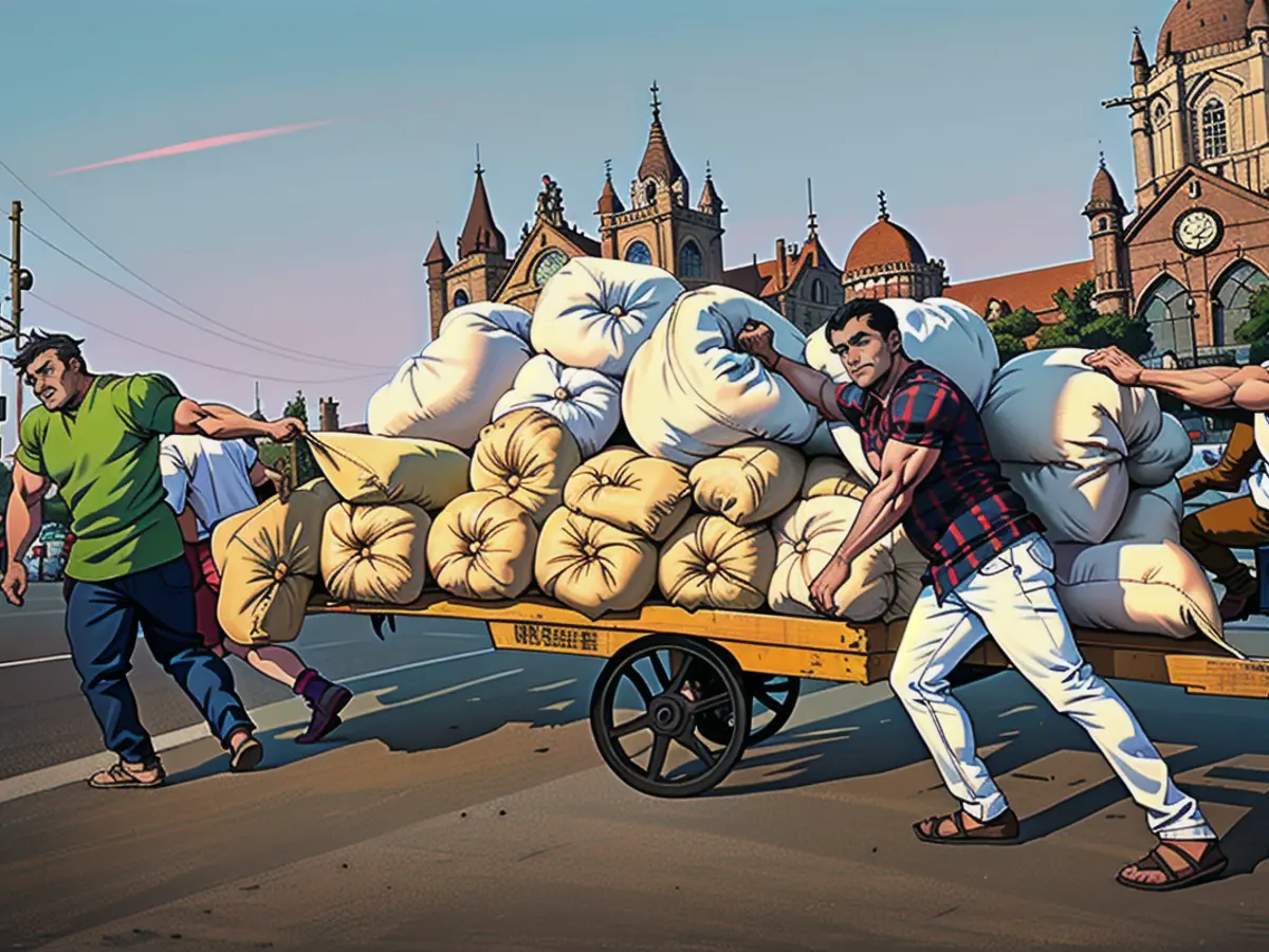 Workers push a cart with packages along a road in front of Victoria Terminus, Mumbai, on April 18, 2024.