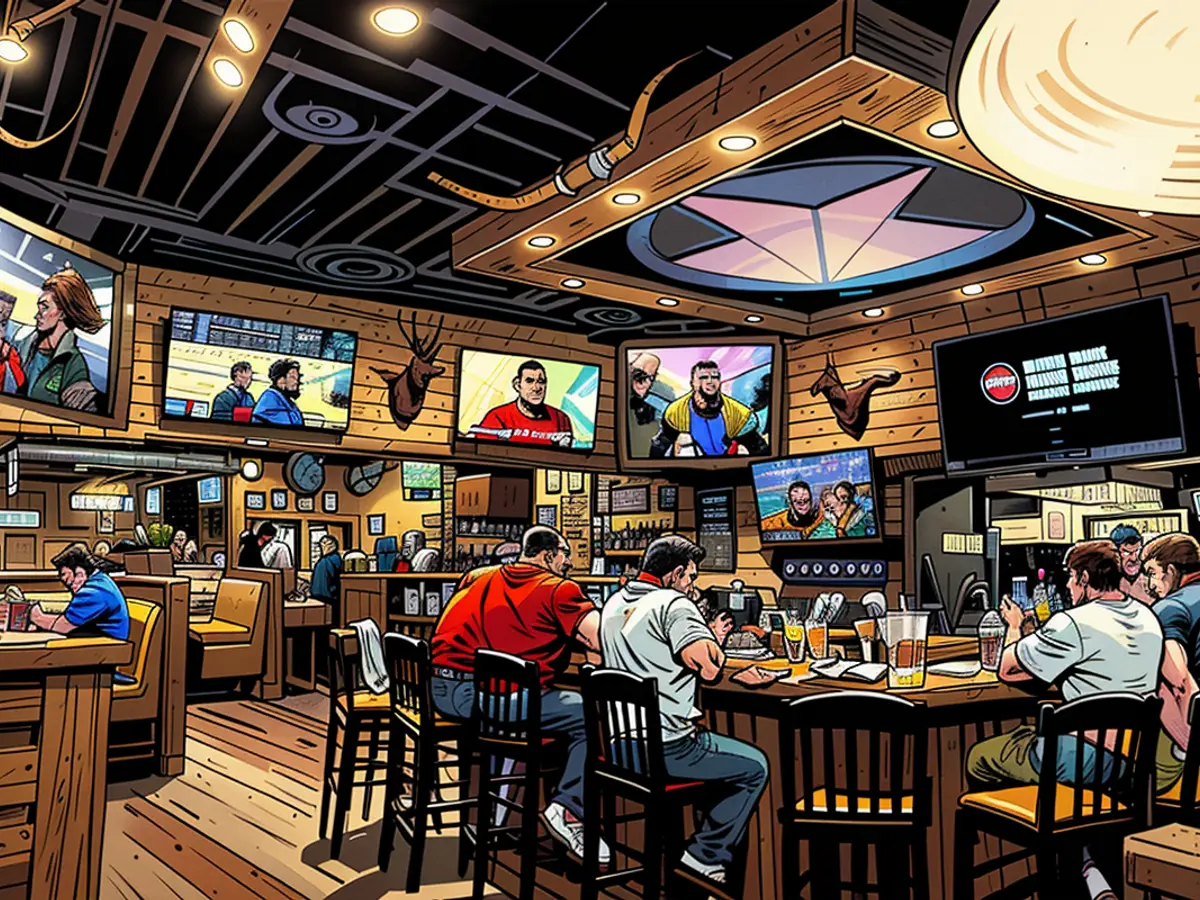 Gäste sitzen an der Bar eines Texas Roadhouse-Restaurants im November 2023 und schauen Sport.