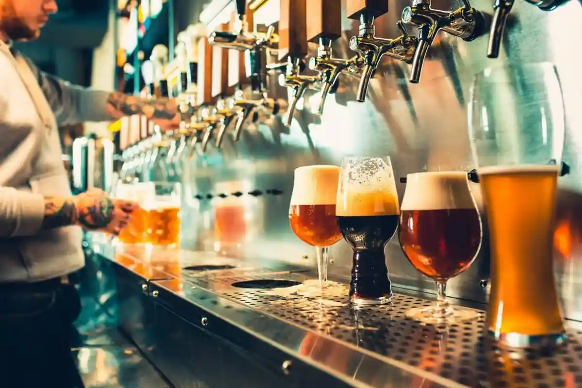 бармен наливает пиво разных видов из крана фото