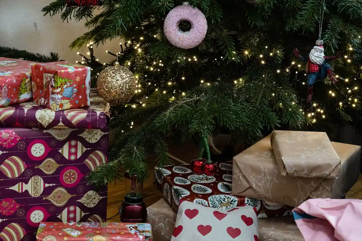 Подарки в канун Рождества:Завернутые подарки лежат под украшенной елкой. В этом году жители Германии хотят быть более экономными в выборе подарков.
